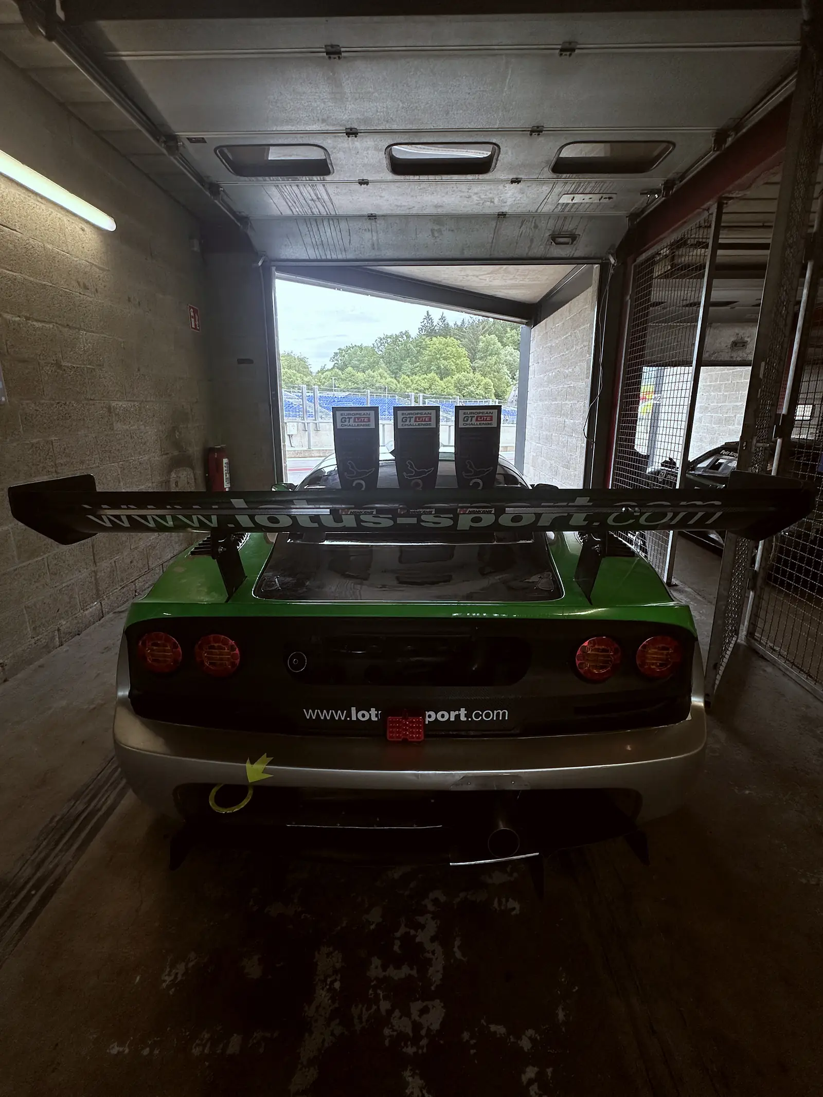 Zelený Exige zezadu v boxu, vrata otevřená, Spa-Francorchamps
