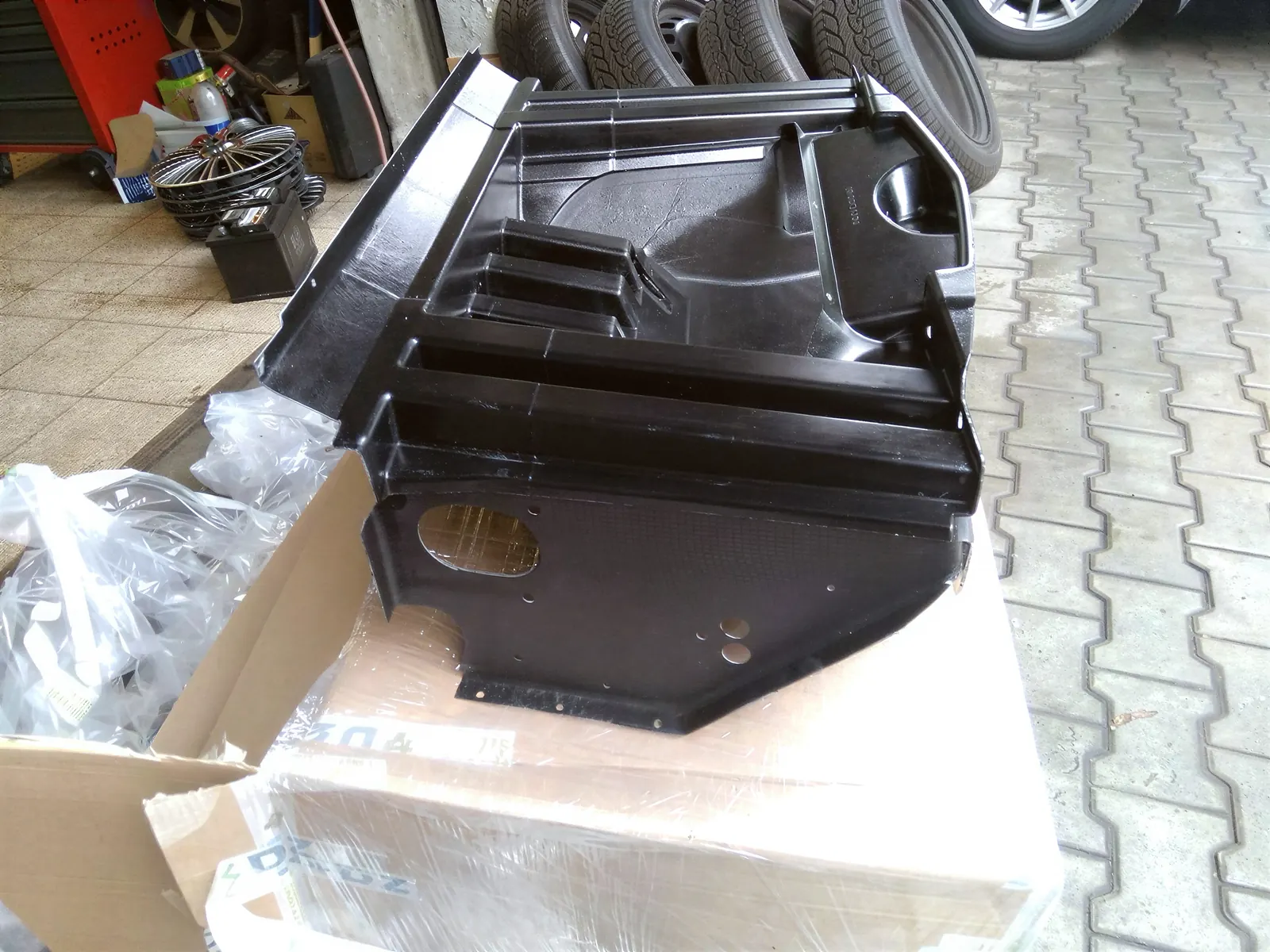Černý kompozitový crash box na paletě před dílnou